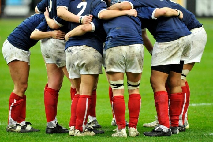 Women rugby players gather in a huddle