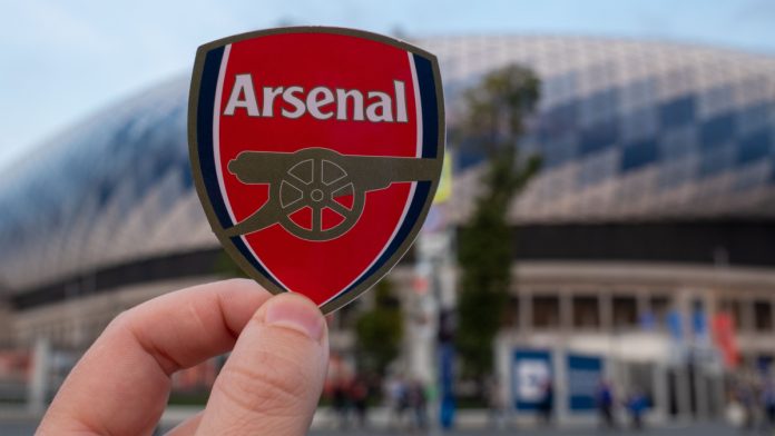 Man holding an Arsenal badge.