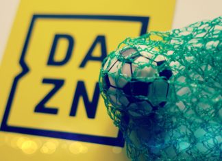 DAZN losses widened in 2023 but firm remains confident in profitability A yellow DAZN sign next to a football in a green net.