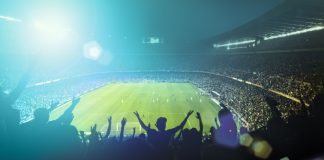 NBC partners with Cosm for “Shared Reality” sports matches Football fans watching a game in a stadium.