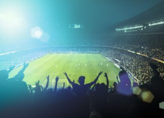 NBC partners with Cosm for “Shared Reality” sports matches Football fans watching a game in a stadium.