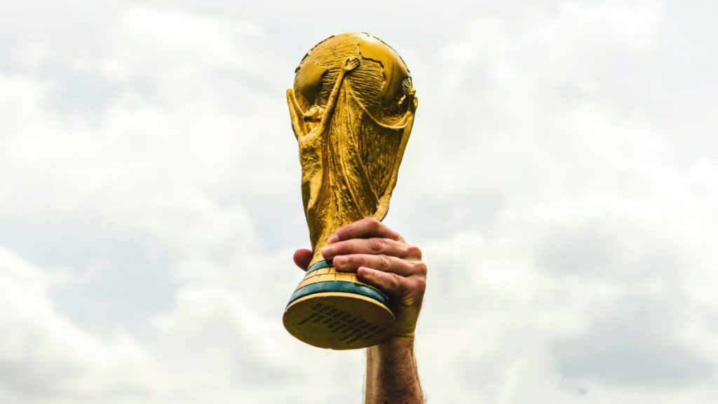 A hand lifting the World Cup trophy.