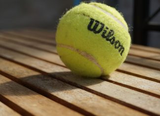 Amer Sports announces IPO of 100 million public shares Wilson tennis ball on a wooden bench.