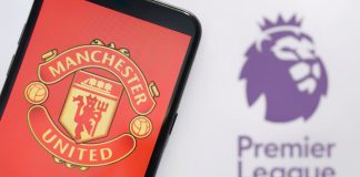 Manchester United achieves record Q2 revenues amid Ratcliffe investment Manchester United on a mobile phone in front of Premier League logo.