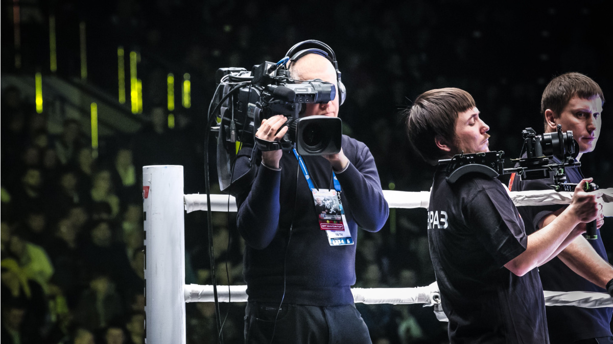 Man holding camera in boxing ring.