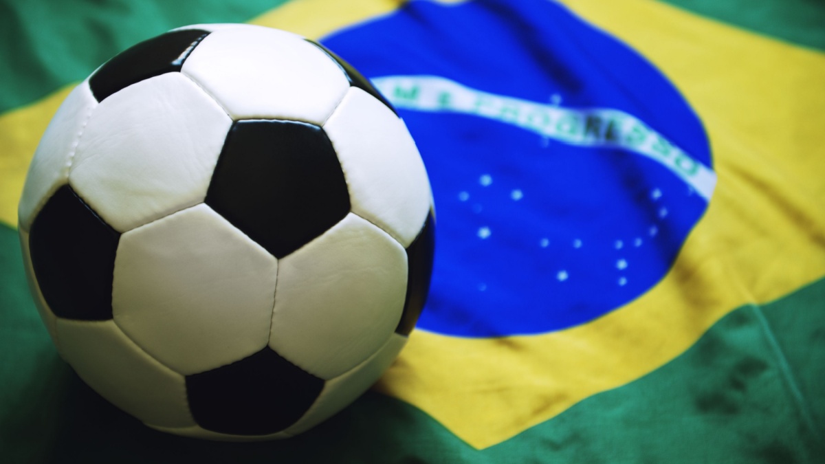 Football sitting on Brazilian flag background.