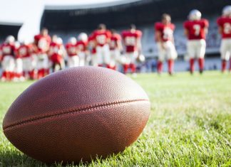 Jon Steinbrecher, MAC: upholding integrity amidst collegiate sports betting boom Close up of an American football on the field, players in the background.
