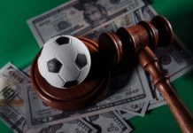 Football tops match-fixing concerns in 2023 Sportradar report Soccer ball and judge gavel on green background close-up.