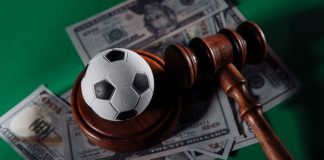 Football tops match-fixing concerns in 2023 Sportradar report Soccer ball and judge gavel on green background close-up.