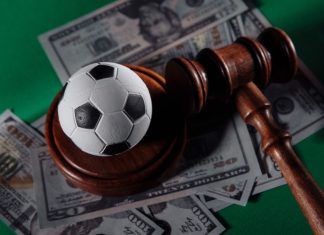 Football tops match-fixing concerns in 2023 Sportradar report Soccer ball and judge gavel on green background close-up.