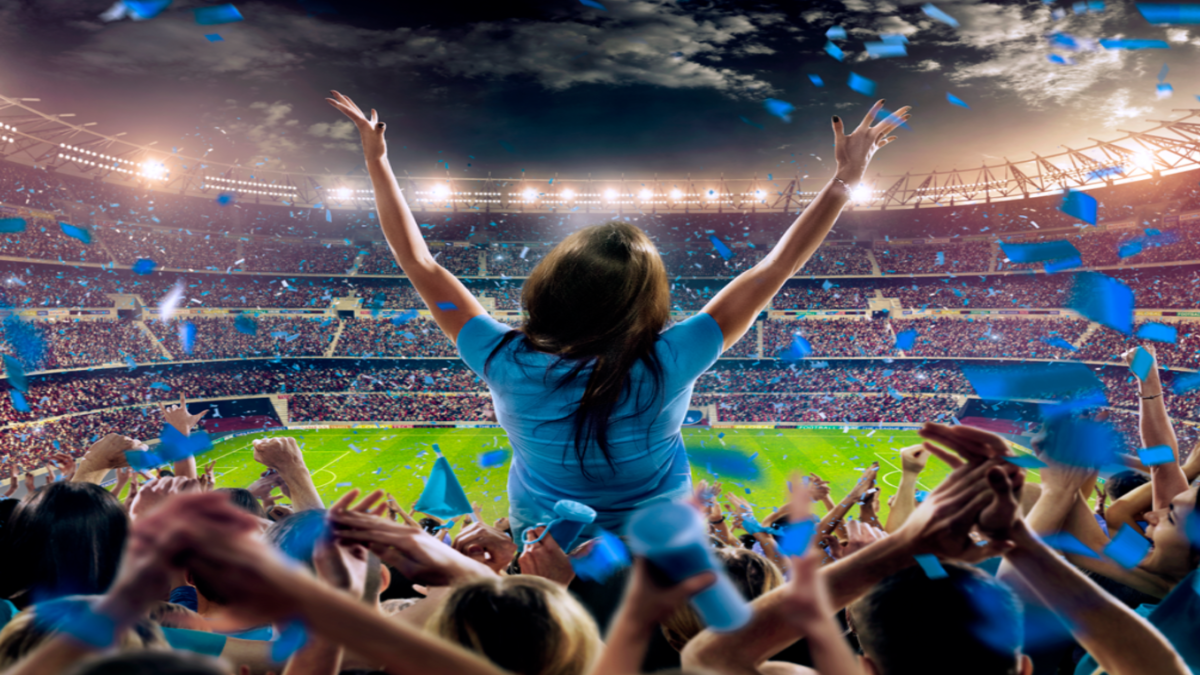 Woman standing in stadium with crowd behind her.