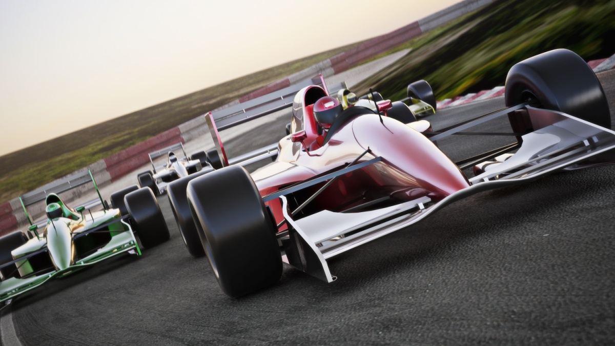 Red race car close up front view on a track leading the pack with motion.