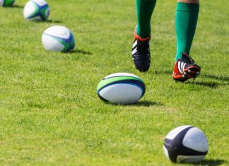 English Premiership Rugby extends flagship title sponsorship Rugby. Balls lying on pitch during workout. Closeup of legs running rugby player.