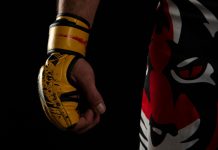 Is match-fixing a threat to MMA? OKTAGON says no Mixed martial arts (MMA) fighter. Detail of the yellow glove with tiger pants on black background.