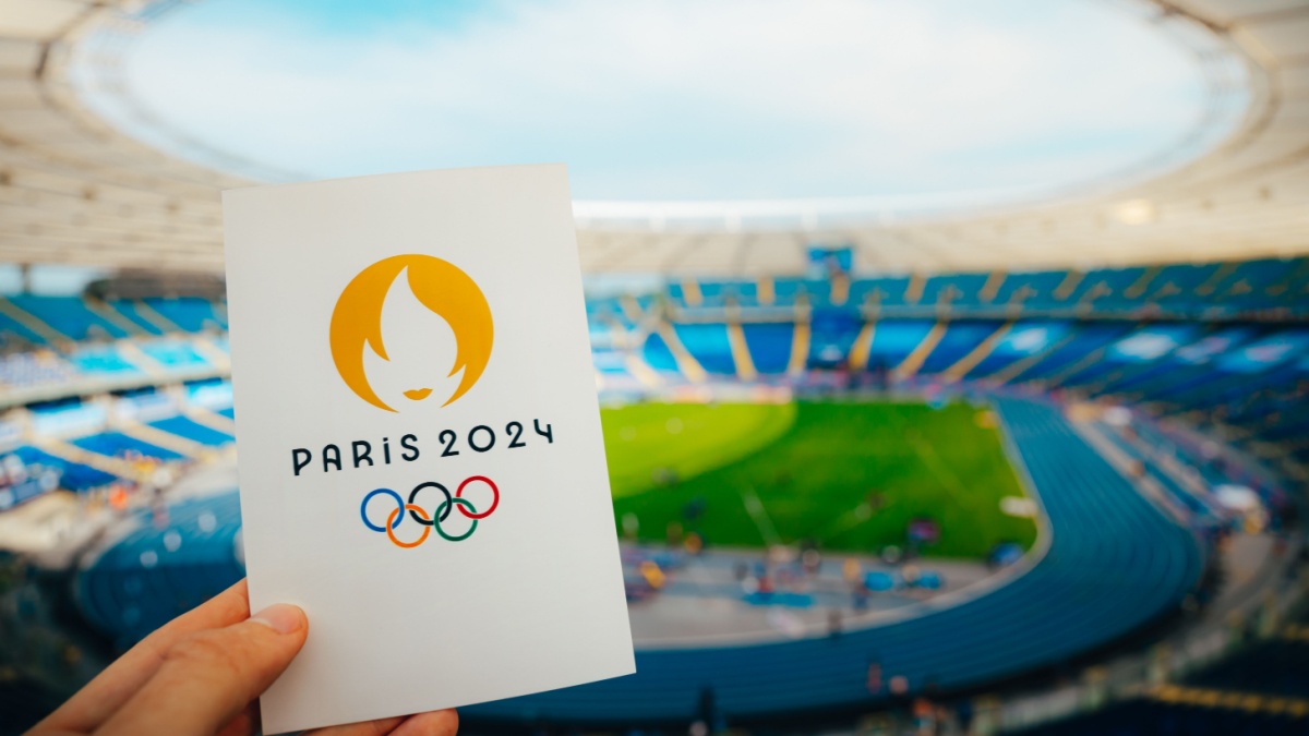 Icon of Summer olympic Games Paris 2024 Held by Athlete. Modern Stadium in background. Wallpaper for Summer Olympic Game in Paris 2024.