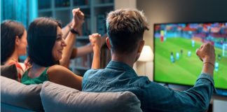 YouGov: UK football fans’ Euro 2024 viewing habits revealed Group of young friends watching a football match on TV together and cheering for their team.