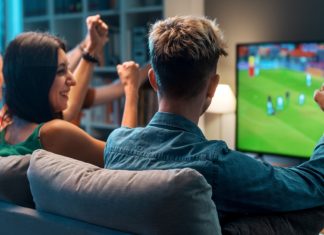 YouGov: UK football fans’ Euro 2024 viewing habits revealed Group of young friends watching a football match on TV together and cheering for their team.
