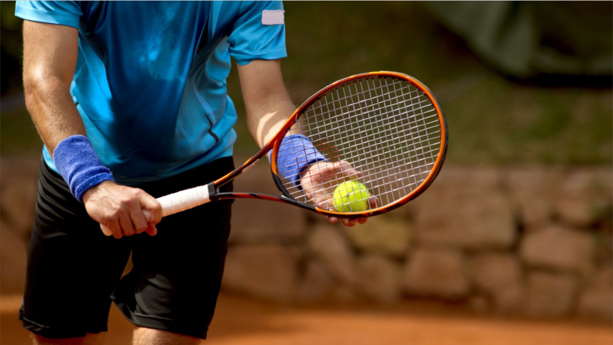 A tennis player prepares to serve a tennis ball during a match.