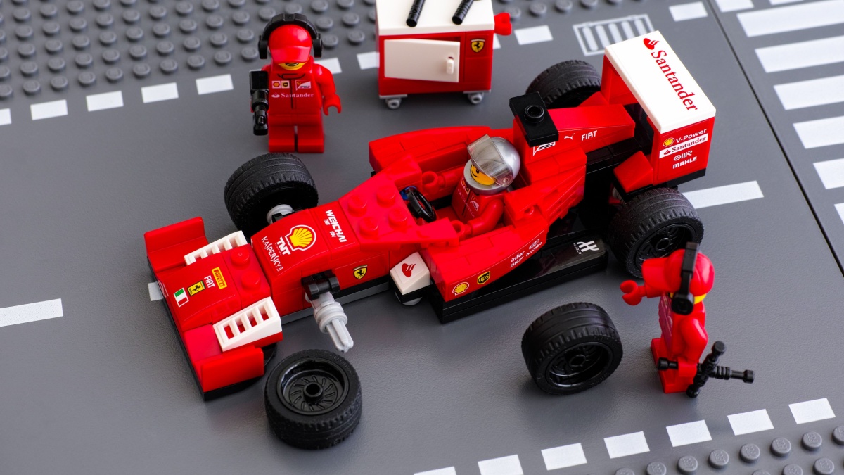 Tambov, Russian Federation - June 23, 2015 Lego team crew members fixing wheel of Lego Speed Champions Ferrari F14 T race car. Studio shot.