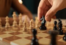 Google’s historic sponsorship sets new chess standards Close-up shot of a hand moving a black chess piece during a game between two players.