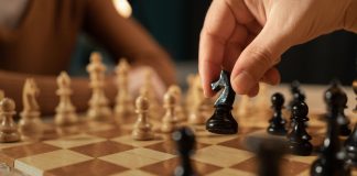 Google’s historic sponsorship sets new chess standards Close-up shot of a hand moving a black chess piece during a game between two players.