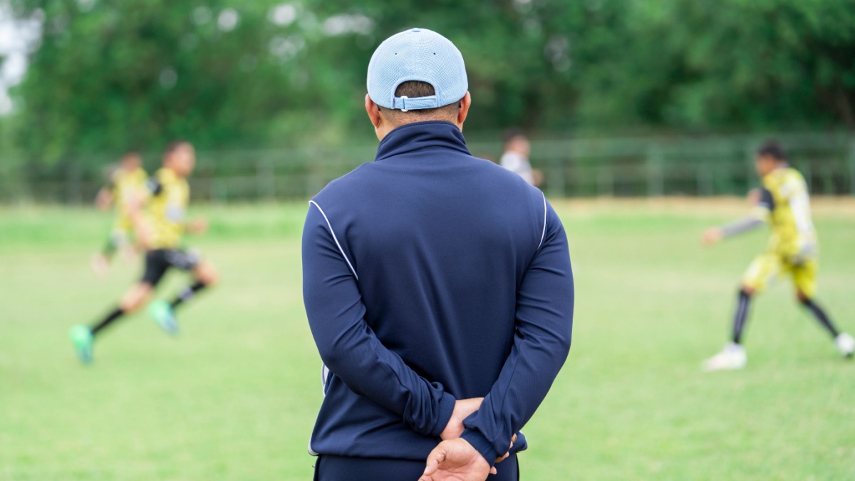 Football or socker coach observing kid football match.