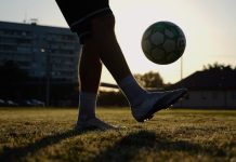 Online trading poised to replace betting sponsorships in football Legs of young man kicking fooball at green field. Male feet of professional footballer juggling soccer ball on stadium at sunset. Sportsman practicing tricks outdoor. Concept of a freestyle football.