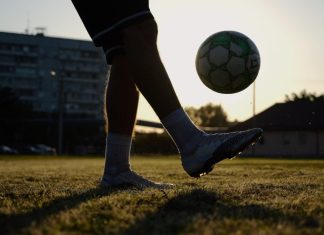 Online trading poised to replace betting sponsorships in football Legs of young man kicking fooball at green field. Male feet of professional footballer juggling soccer ball on stadium at sunset. Sportsman practicing tricks outdoor. Concept of a freestyle football.