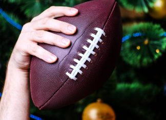 NFL reportedly gives Netflix and Amazon Prime nod for Christmas Day hand holding American football ball on Christmas tree background.