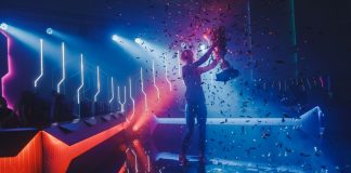 Riot Games introduces new betting policy for esports eSports Winner Trophy Standing on a Stage in the Middle of the Computer Video Games Championship Arena. Two Rows of PC for Competing Teams. Stylish Neon Lights with Cool Area Design.