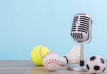 iGaming Daily: Insider Sport’s highlights and predictions Concept sports commentator : The retro microphone put on the wooden table with football or soccer , tennis ball , baseball and shuttlecock isolated on blue background.