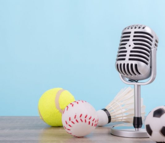 iGaming Daily: Insider Sport’s highlights and predictions Concept sports commentator : The retro microphone put on the wooden table with football or soccer , tennis ball , baseball and shuttlecock isolated on blue background.