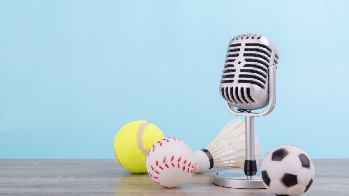Concept sports commentator : The retro microphone put on the wooden table with football or soccer , tennis ball , baseball and shuttlecock isolated on blue background.