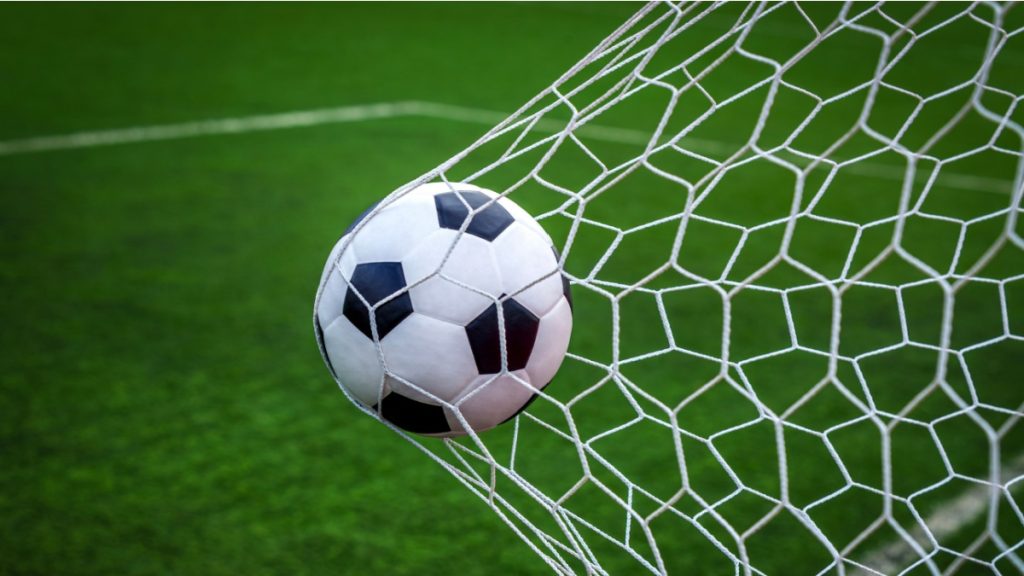 Football on goal with net background, football player shoot a leather foot ball for make a score, Peru.