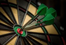 Darts drive Matchroom Sports profits as boxing fights for growth Darts board with three darts in the bullseye.