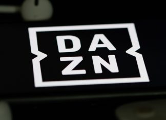 DAZN targets $5bn revenue goal amid streaming battle Rheinbach, Germany 5 June 2021, The logo of the streaming service "DAZN" on the screen of a smartphone with white headphones and a remote control.