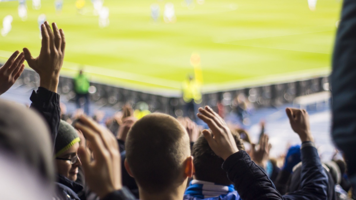 Fans clapping their hands at a football stadium.