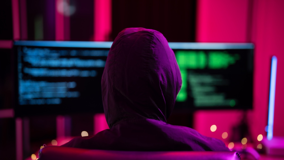 Black Hat Hacker hoodie concept at a laptop computer hacking the Internet. Cyber crime and security principles.