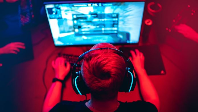 Professional e-sport studio room with personal computer armchair, keyboard for stream in neon color blur background. Soft focus.