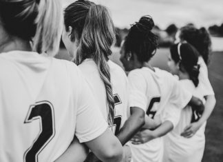 Damning report uncovers football’s discrimination crisis Female football players huddling together.