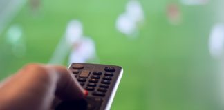 Q&A: Sports streaming tactics ahead of 2026 FIFA World Cup Man holding remote control for TV while there is football on television representing leisure watching sports.