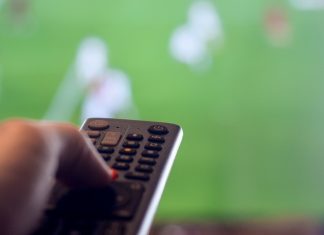 Q&A: Sports streaming tactics ahead of 2026 FIFA World Cup Man holding remote control for TV while there is football on television representing leisure watching sports.