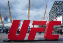 UFC gym denies FBI raid after Dulgarian match-fixing claims London, UK. April 2, 2025. The O2 Arena in London features its iconic dome and yellow masts, a red UFC sign in the foreground, modern buildings, and a cloudy sky above.