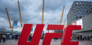 UFC gym denies FBI raid after Dulgarian match-fixing claims London, UK. April 2, 2025. The O2 Arena in London features its iconic dome and yellow masts, a red UFC sign in the foreground, modern buildings, and a cloudy sky above.