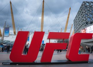 UFC gym denies FBI raid after Dulgarian match-fixing claims London, UK. April 2, 2025. The O2 Arena in London features its iconic dome and yellow masts, a red UFC sign in the foreground, modern buildings, and a cloudy sky above.