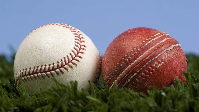 Baseball-and-Cricket ICC cricket ball and baseball on grass with blue sky - illustration of the way things change. Baseball is an evolution of cricket