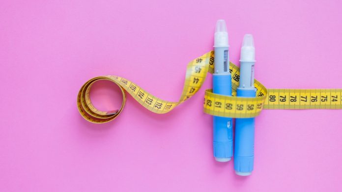 Insulin pens wrapped in a measuring tape on a pink surface, illustrating healthcare, weight management, and chronic illness support. drugs injection ozempic for weight loss