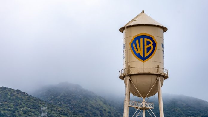Warner-Bros Burbank, USA, Mar 12, 2023 – The iconic Warner Bros. water tower featuring the WB logotype on the studio lot in California, with low clouds and green hills in the background.