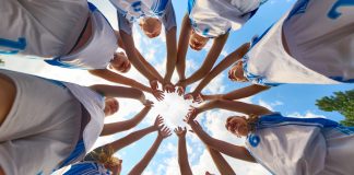Women’s sport has won visibility – now it must win value Women basketball team shows solidarity by forming a supportive circle beneath a clear sky. Concept of shared focus, youth rituals in sport, fitness education, marketing for athletic brands.