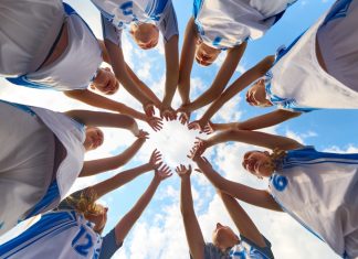 Women’s sport has won visibility – now it must win value Women basketball team shows solidarity by forming a supportive circle beneath a clear sky. Concept of shared focus, youth rituals in sport, fitness education, marketing for athletic brands.